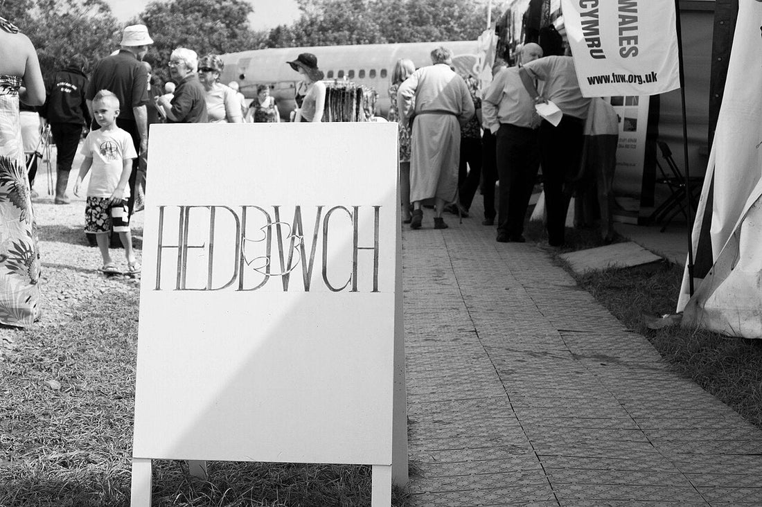 white sign displaying the Welsh word "Heddwch", meaning "Peace", at the 2012 National Eisteddfod in the Vale of Glamorgan. Photo by Rhys Brooks, licensed under CC BY 2.0.