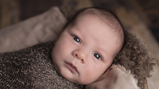 A sleeping newborn baby wrapped in a light blanket.