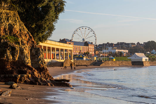 Barry Island seafront at golden hour, with the beach, promenade buildings and Ferris wheel overlooking Whitmore Bay.