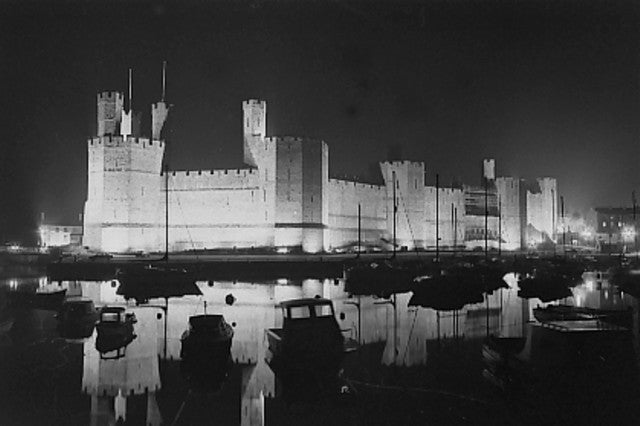 Caernarfon Castle and harbour illuminated at night