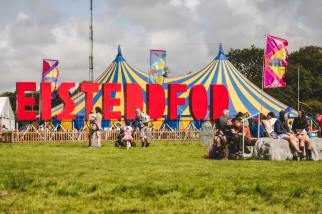 A large Eisteddfod sign beside a blue and yellow festival tent
