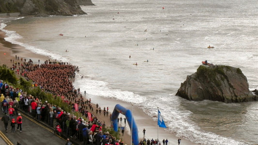 IRONMAN Wales athletes assembling on Tenby's North Beach beside Goscar Rock