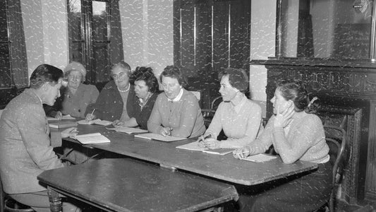 Adult Welsh learners seated around a table during a class in Cemaes in 1958
