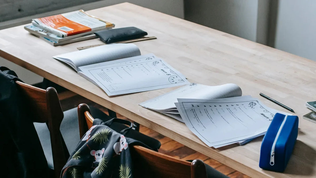 School books, worksheets and pencil cases arranged on a classroom desk