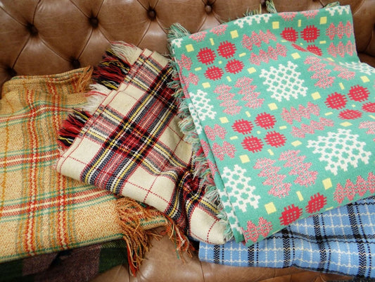 Assorted traditional Welsh woollen blankets in green, pink, blue and checked patterns.