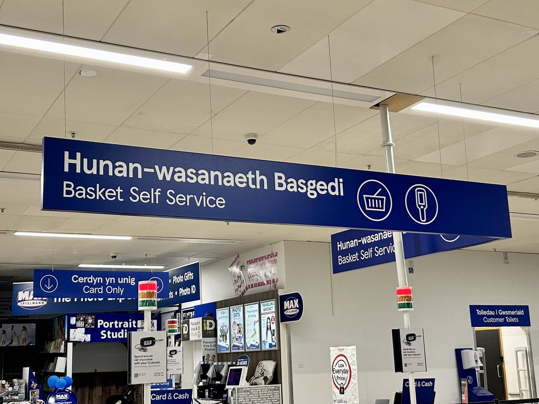 Bilingual Welsh and English directional signs inside a supermarket in Wales
