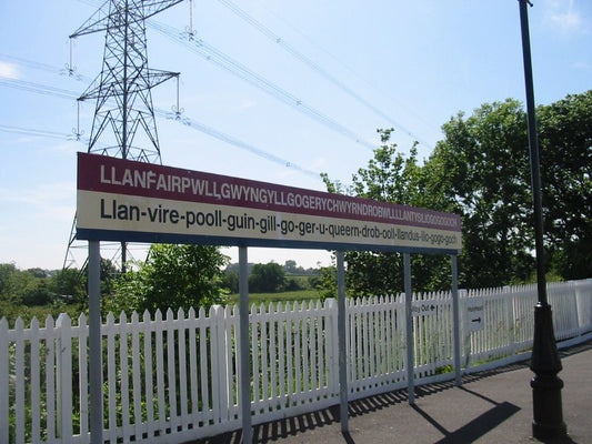 Railway station sign at Llanfairpwll showing the long Welsh place name and an English-speaker pronunciation guide