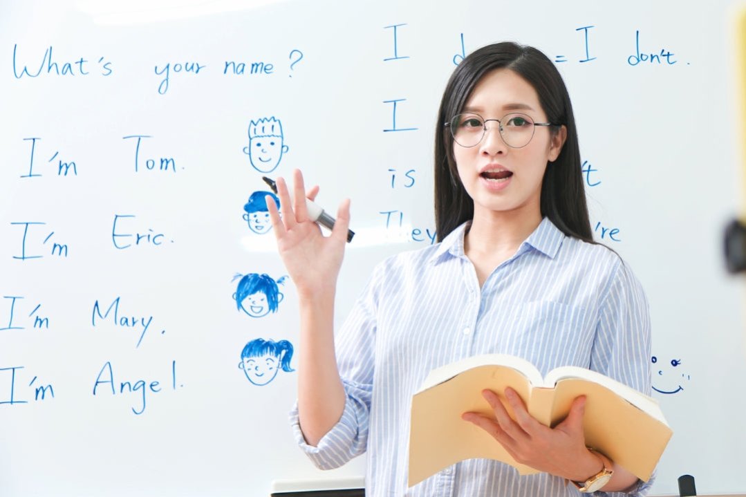 a woman teaching English on a whiteboard